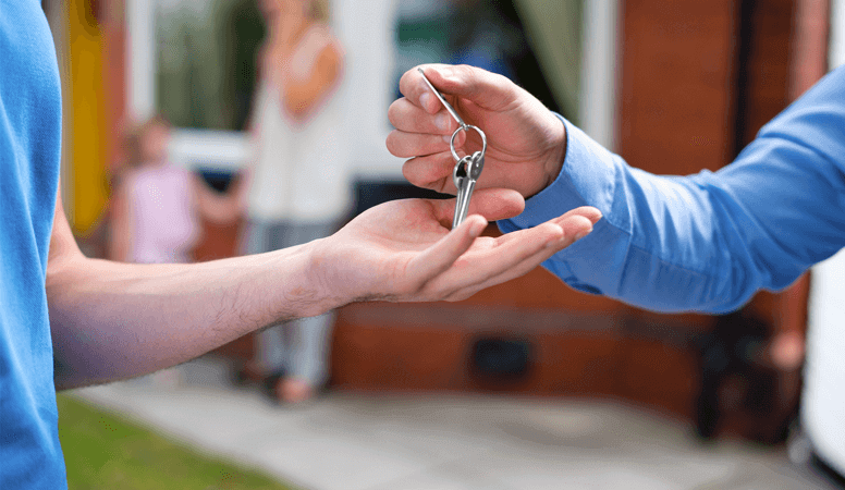 An outstretched hand, receiving a pair of house keys for their new home