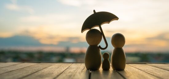 A wooden carving, of a 3-person family holding an umbrella over their heads