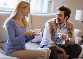 A young couple, smiling at one another while drinking from tea cups