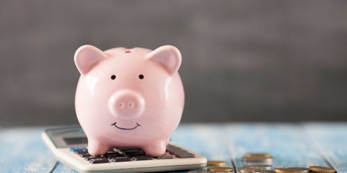 A pink piggy bank, sitting on top of a calculator