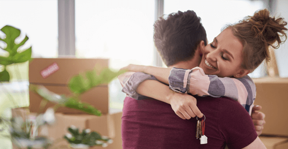 A young couple hugging, holding the keys to their new home