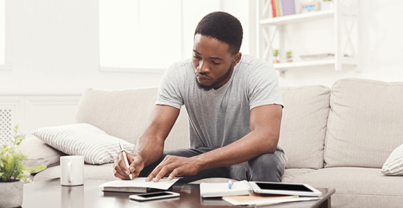 A young man, writing in a notepad