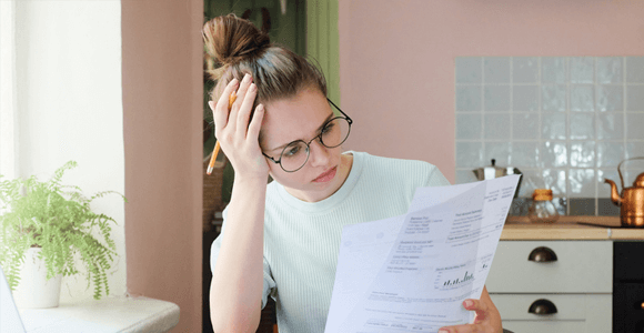 A lady, looking confused while holding paper documents