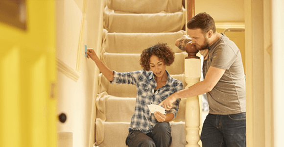 A young couple, deciding what colour to paint a wall in their new home