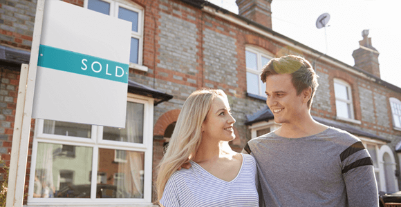 A young couple, standing in front of their newly purchased home