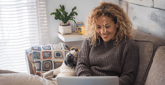 A woman, wearing a grey sweater, while using a laptop