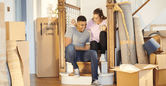 A young couple, sitting in their newly purchased home, surrounded by boxes