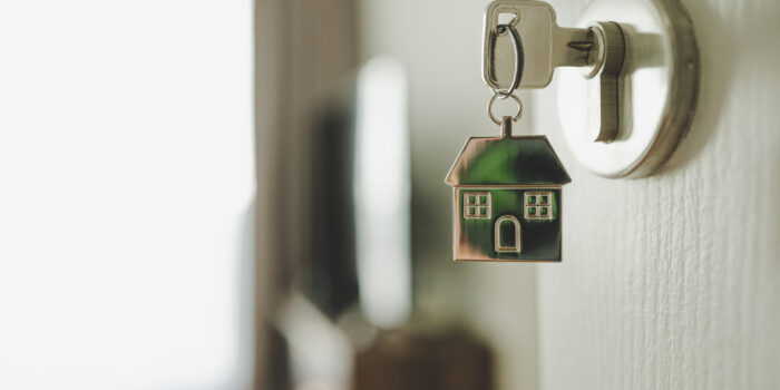 a key sitting in a lock, with a keyring of a house hanging from it