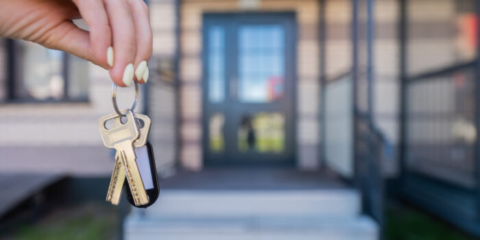 A hand holding a pair of house keys